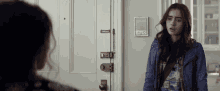a woman in a blue jacket is standing in front of a door with a lock on it