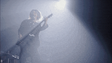 a man playing a guitar in a dark room with the letter d on the bottom