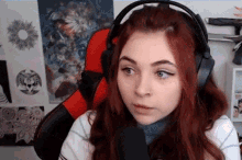 a girl with red hair is wearing headphones and sitting in a chair .