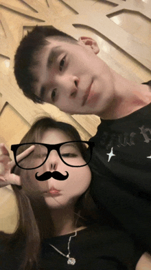 a man and a woman pose for a picture with a fake mustache and glasses on