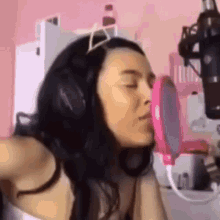 a woman is kissing a pink mirror in front of a microphone in a room .