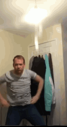 a man in a striped shirt is standing in front of a closet