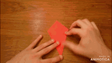 a person is holding a piece of red paper with the words made in animatica on the bottom right