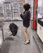 a woman is standing next to a cockroach on a leash in a grocery store .