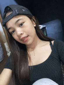 a girl wearing a black shirt and a black hat looks at the camera