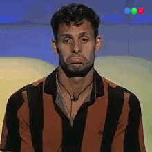 a man wearing a striped shirt with a necklace around his neck is making a funny face