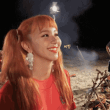 a woman with red hair is smiling in front of a fire .