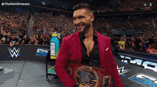 a man in a pink suit holds a wrestling championship