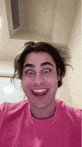 a young man wearing a pink shirt makes a funny face