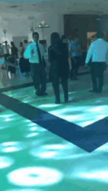 a group of people dancing on a dance floor with green lights