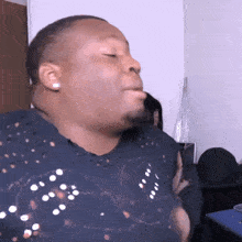a man in a black shirt is making a funny face while sitting in a room .