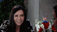 a woman is smiling while sitting at a table with flowers