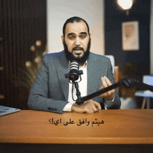 a man with a beard is sitting at a desk with a microphone in front of him
