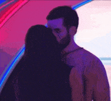a man and a woman are kissing in a dark room with neon lights