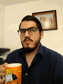 a man with glasses and a beard is holding a mug with the simpsons on it