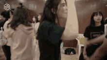 a group of young women are standing in a room dancing .