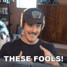 a man wearing headphones and a hat that says these fools on it
