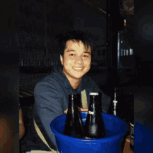 a man is drinking from a bottle in a blue bucket ..