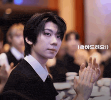 a man in a black shirt and white collar is clapping
