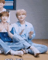 a group of young men are sitting on the floor waving their hands
