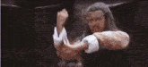 a man with a beard is holding another man 's arm in a boxing match .