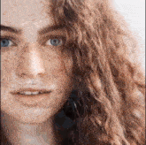 a close up of a woman 's face with freckles and long red hair