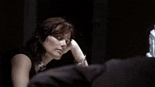 a woman in handcuffs sits at a table with her head on her hand