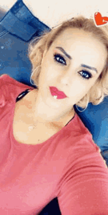 a woman in a red shirt is taking a selfie on a couch .
