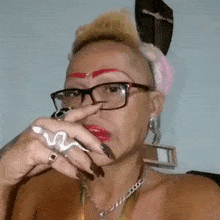 a woman wearing glasses and a snake ring is holding her nose