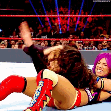 two women are wrestling in a ring and one is wearing a pair of boots that say ' wwe ' on them