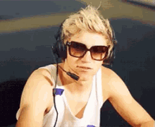 a young man wearing sunglasses and headphones looks at the camera