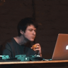 a man is sitting at a desk with an apple laptop