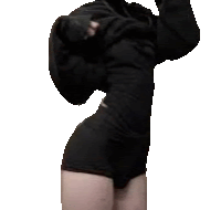 a woman in a black dress and shorts is taking off her hoodie .
