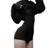 a woman in a black dress and shorts is taking off her hoodie .