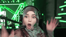 a woman wearing a hijab and headphones looks surprised