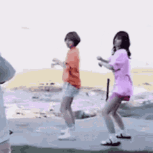 two young women are dancing on a sidewalk .