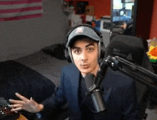 a man in a suit and hat is talking into a microphone .