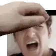 a person is covering a man 's face with their hand while he screams .
