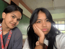 two girls are posing for a picture and one has a lanyard around her neck that says kingz college of the building