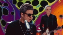 a man is singing into a microphone while another man plays a guitar