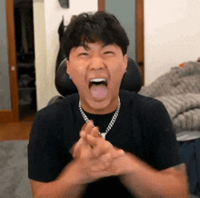 a man is making a funny face with his tongue out while wearing a necklace .