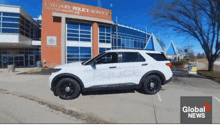 a white police car is parked in front of a calgary police service building
