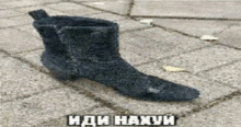 a black boot is sitting on a brick sidewalk with russian writing .