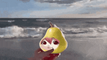 a person is holding a yellow pear with a face on it on the beach .