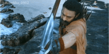 a man holding a sword in front of a body of water