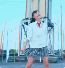 a girl in a school uniform is dancing in front of a tower