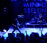 a man singing into a microphone on stage in front of a sign that says selfie