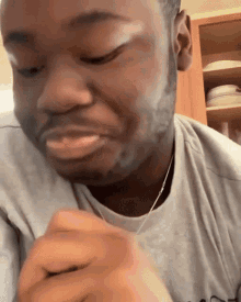 a man with a beard is wearing a grey shirt that says ' a ' on the front