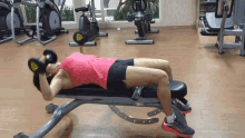 a woman is laying on a bench lifting a dumbbell