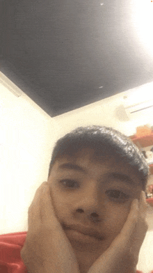 a young boy with his hands on his face is making a funny face